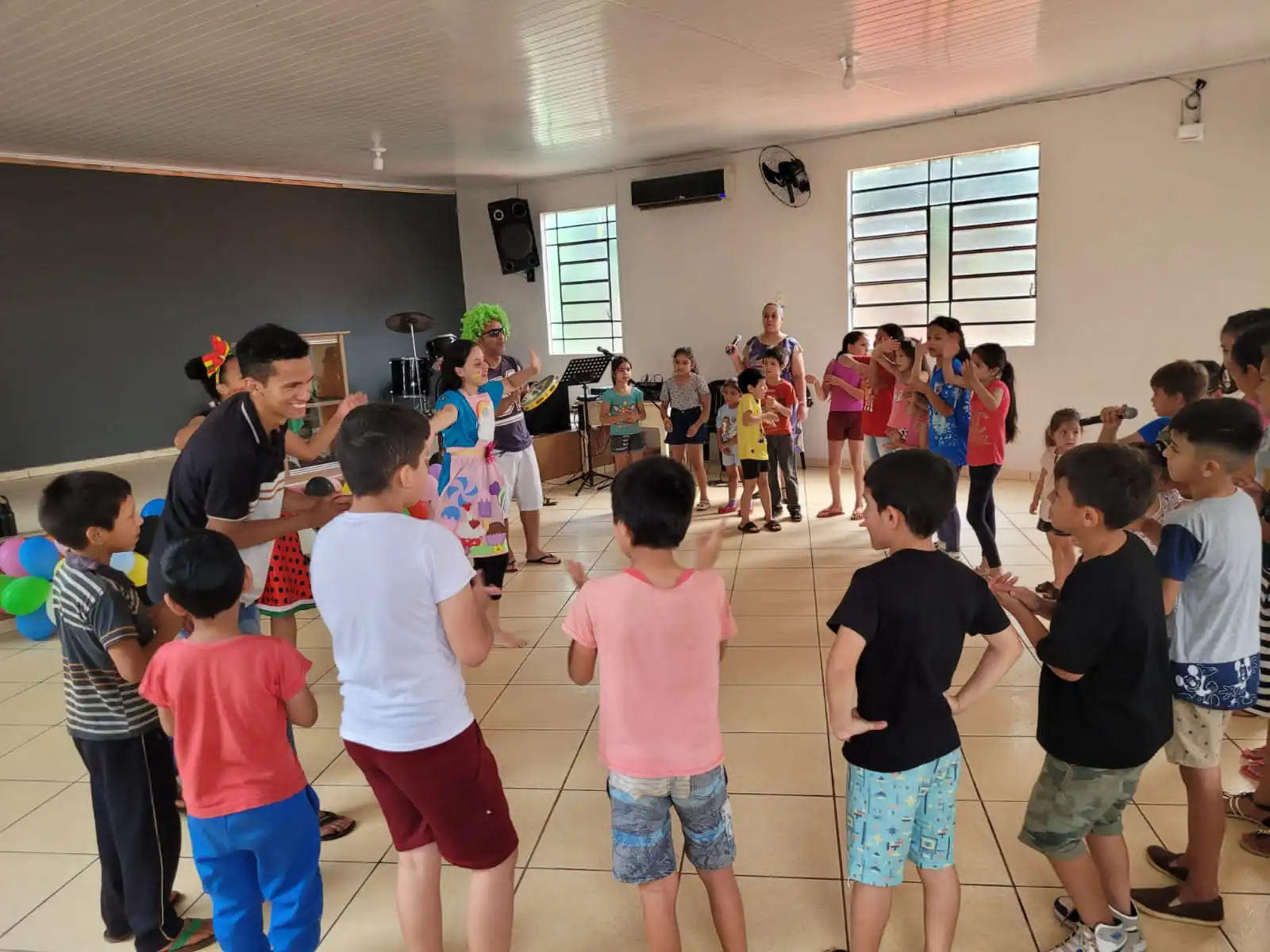 Crianças carentes e voluntários fazendo brincadeiras dentro da igreja em um dia de festa